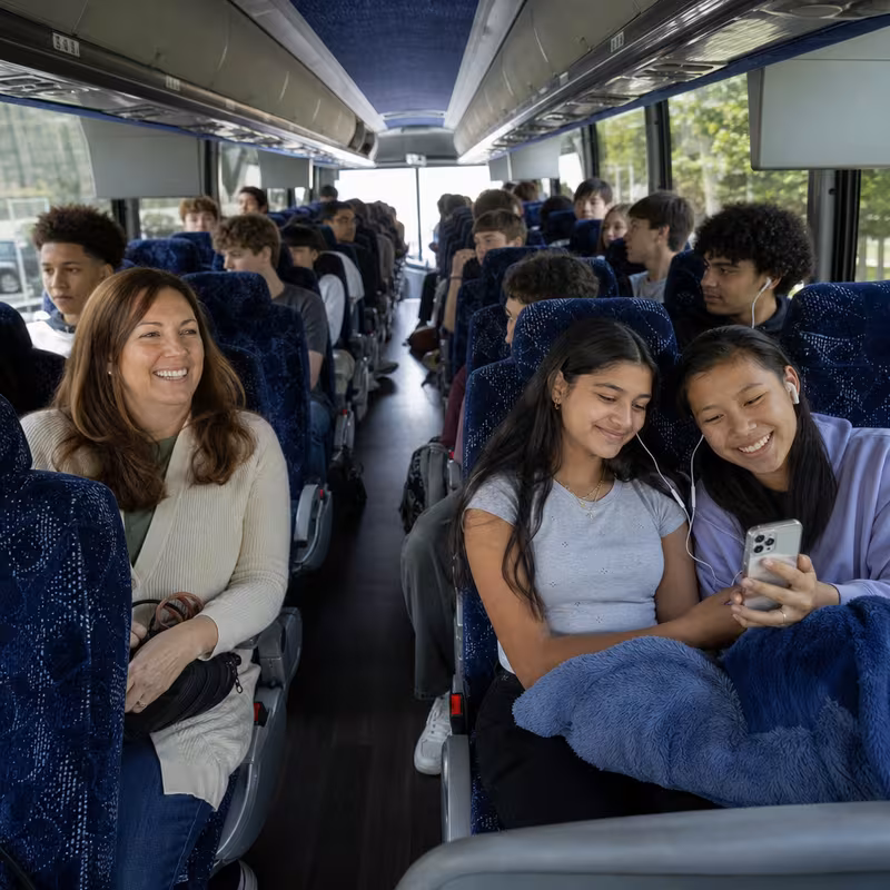 Group boarding a white charter bus for School Transportation transportation in Phoenix